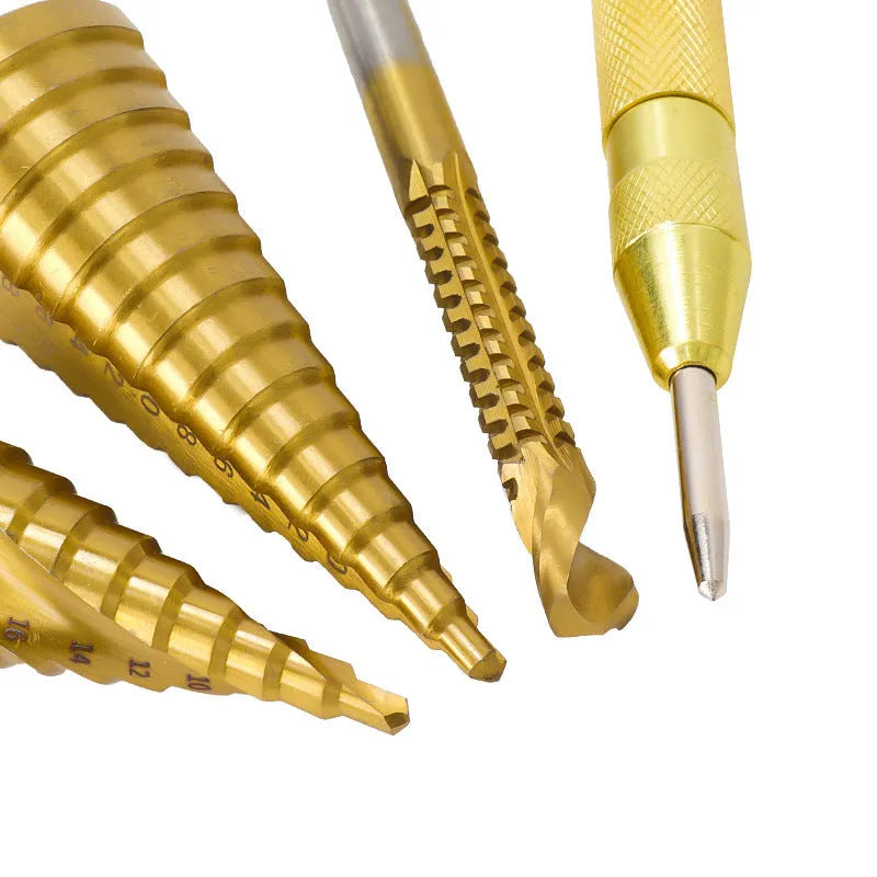 High-speed steel cone step drill bits and a centre punch laid out on a workbench.