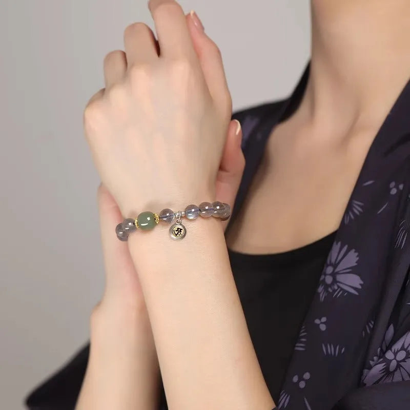 Close-up of a women's bracelet with 8mm moonstone beads and an electroplated Kwan-yin mouse charm.