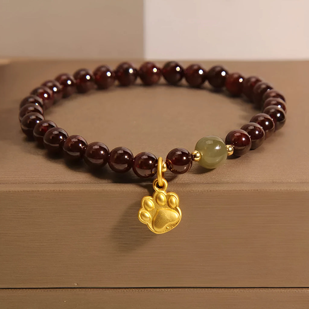 Women's crystal bracelet with a cat's paw garnet design on a polished metal setting.