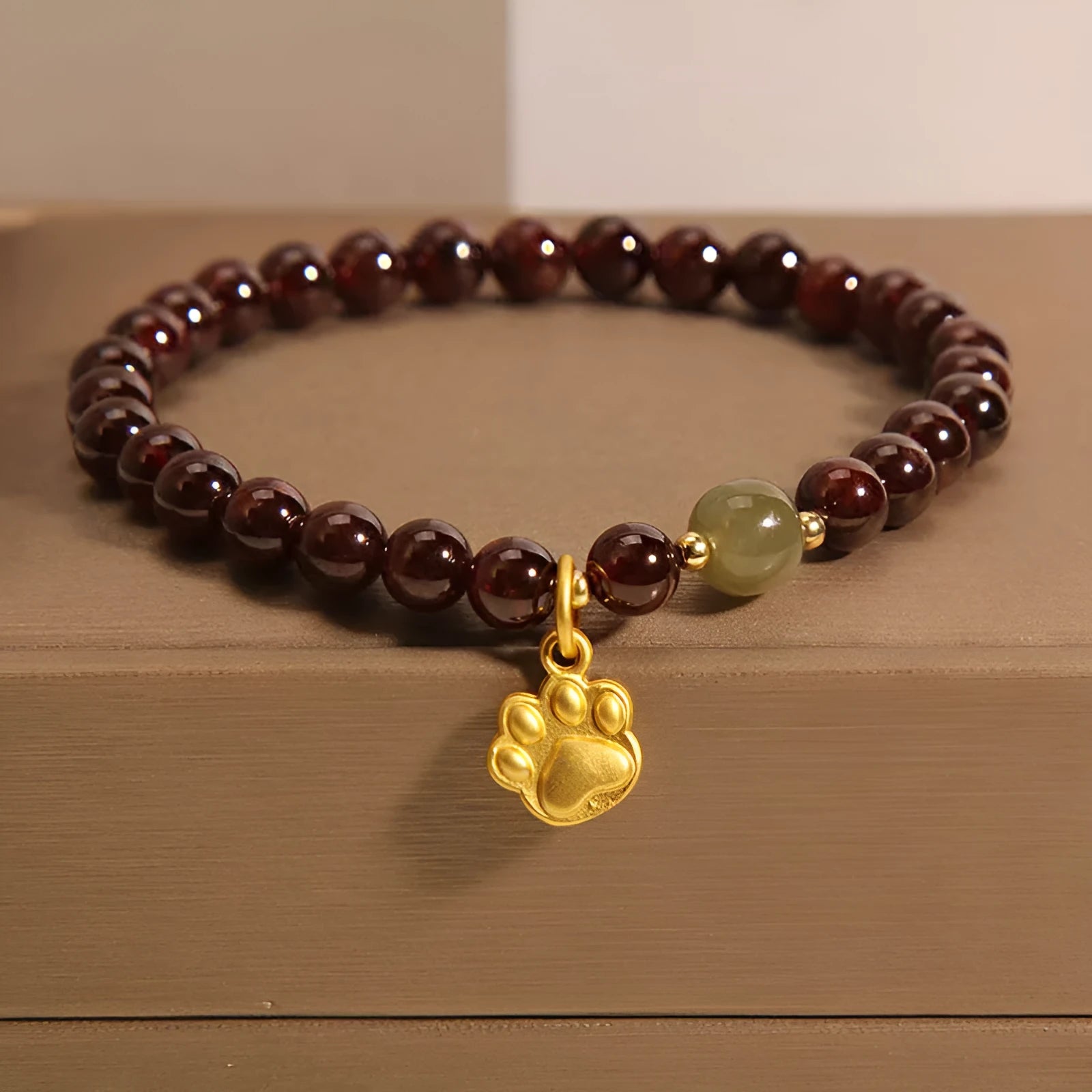 Women's crystal bracelet with a cat's paw garnet design on a polished metal setting.