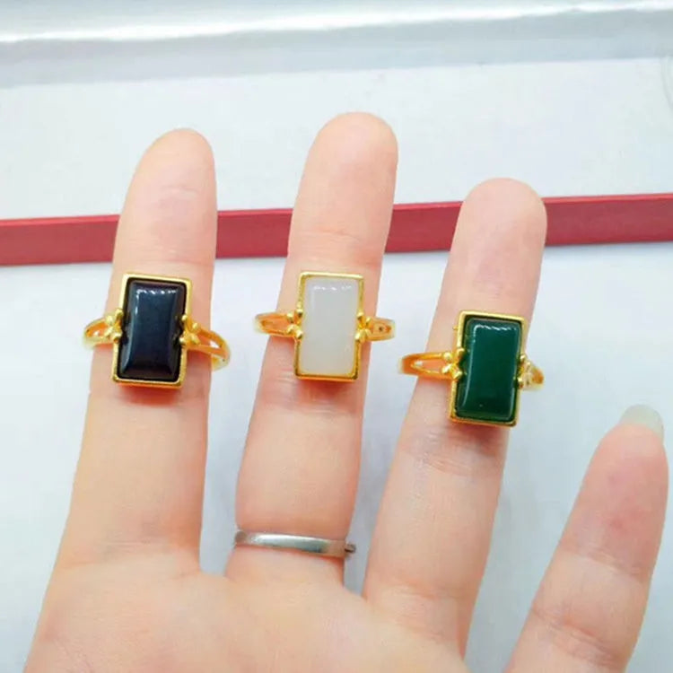 A gold-plated brass ring with an adjustable band and a central green artificial gemstone, in a national style.
