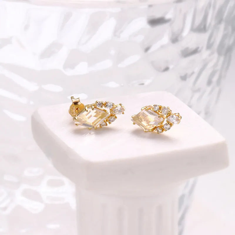 A pair of geometric sterling silver earrings with sweet white crystal studs on a white background.