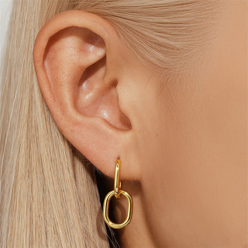 A pair of round, gold-toned brass diamond earclip earrings on a white background.