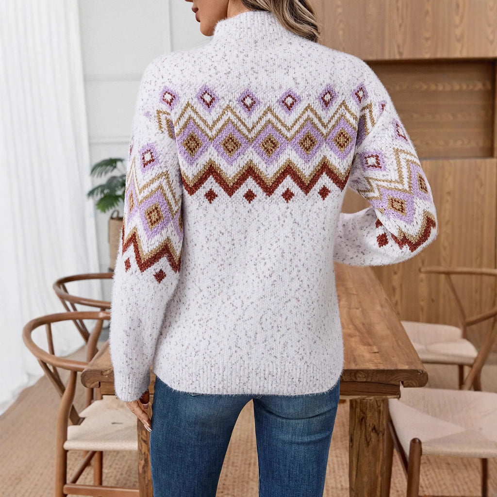 White geometric jacquard half turtleneck loose fit sweater on a hanger, showing long sleeves and textured fabric.