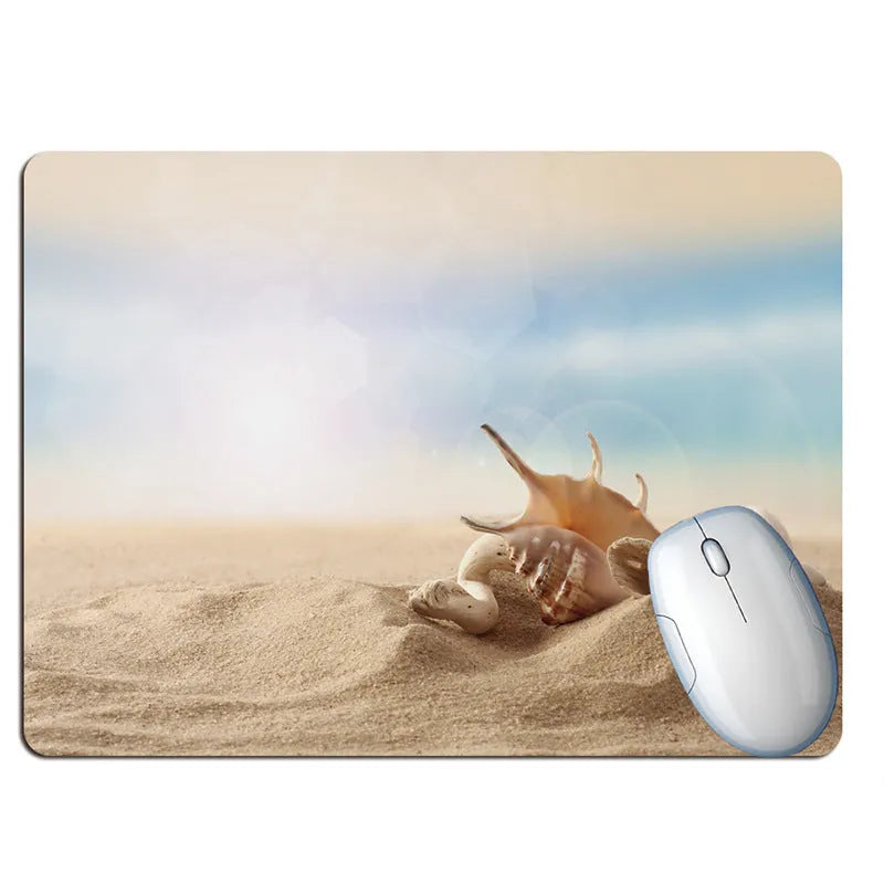 A rubber mouse pad with a colourful Wishing Bottle summer beach holiday design, shown on a desk.