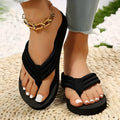 Black women's flat slippers with cotton upper and non-slip EVA sole on a beach background.
