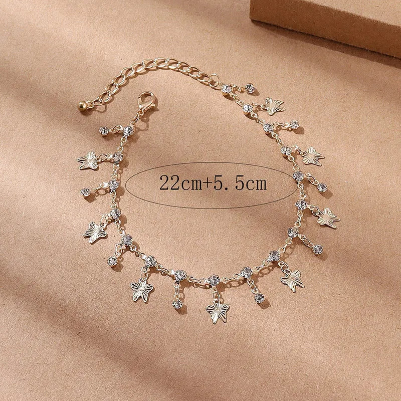 Gold alloy butterfly tassel anklet with colourful floral and leaf design on foot for summer beach wear