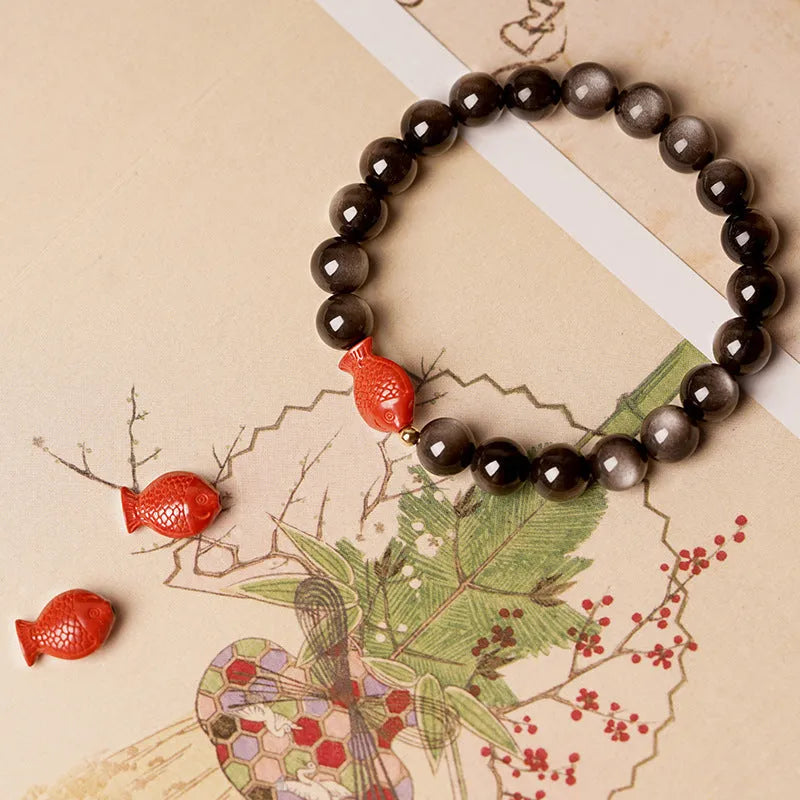 Natural obsidian round bead bracelet with a red cinnabar fungus charm, showing different bead size options.