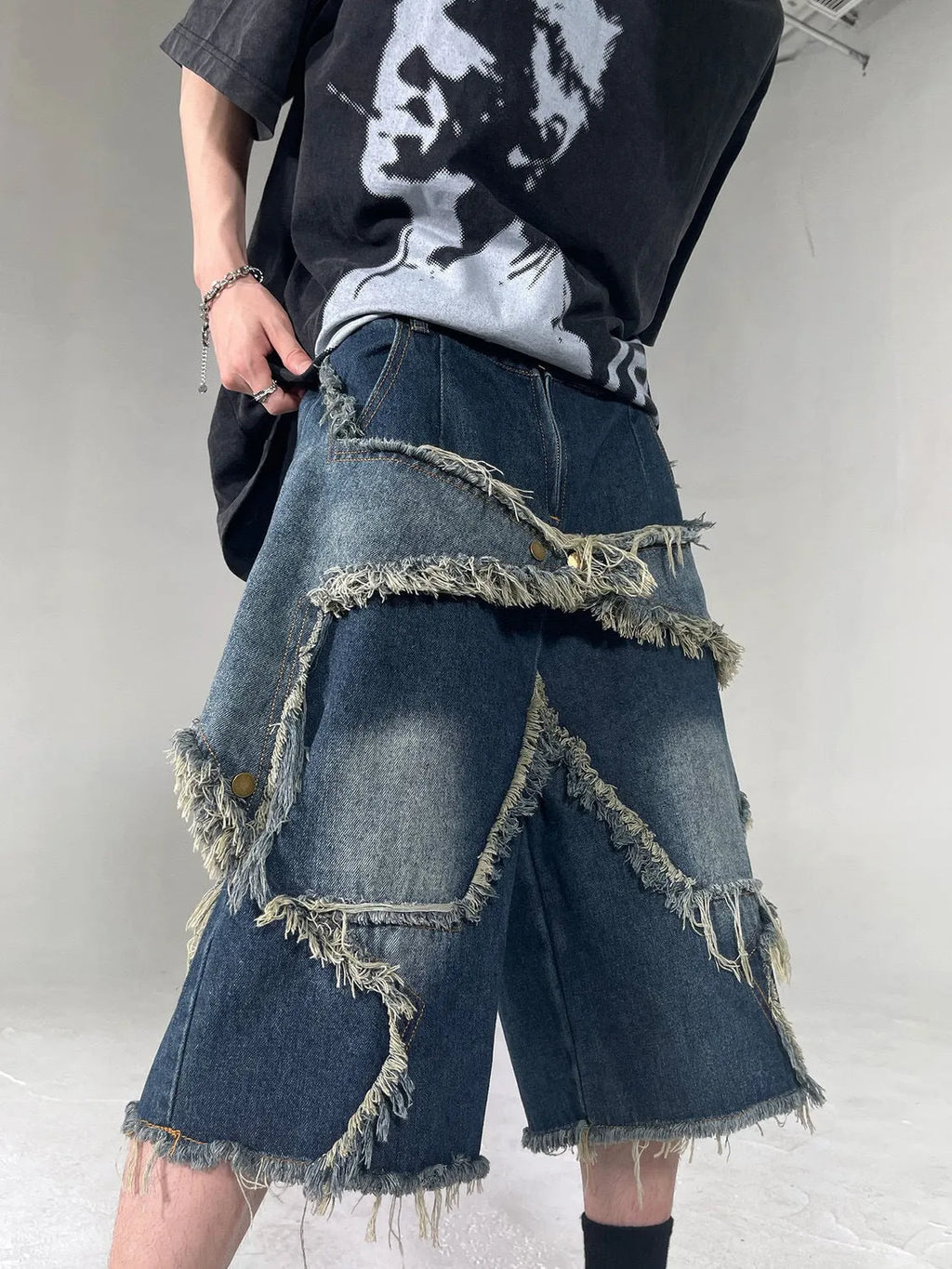 Blue denim shorts with a frayed hem and a large five-pointed star design on the leg, shown on a model.