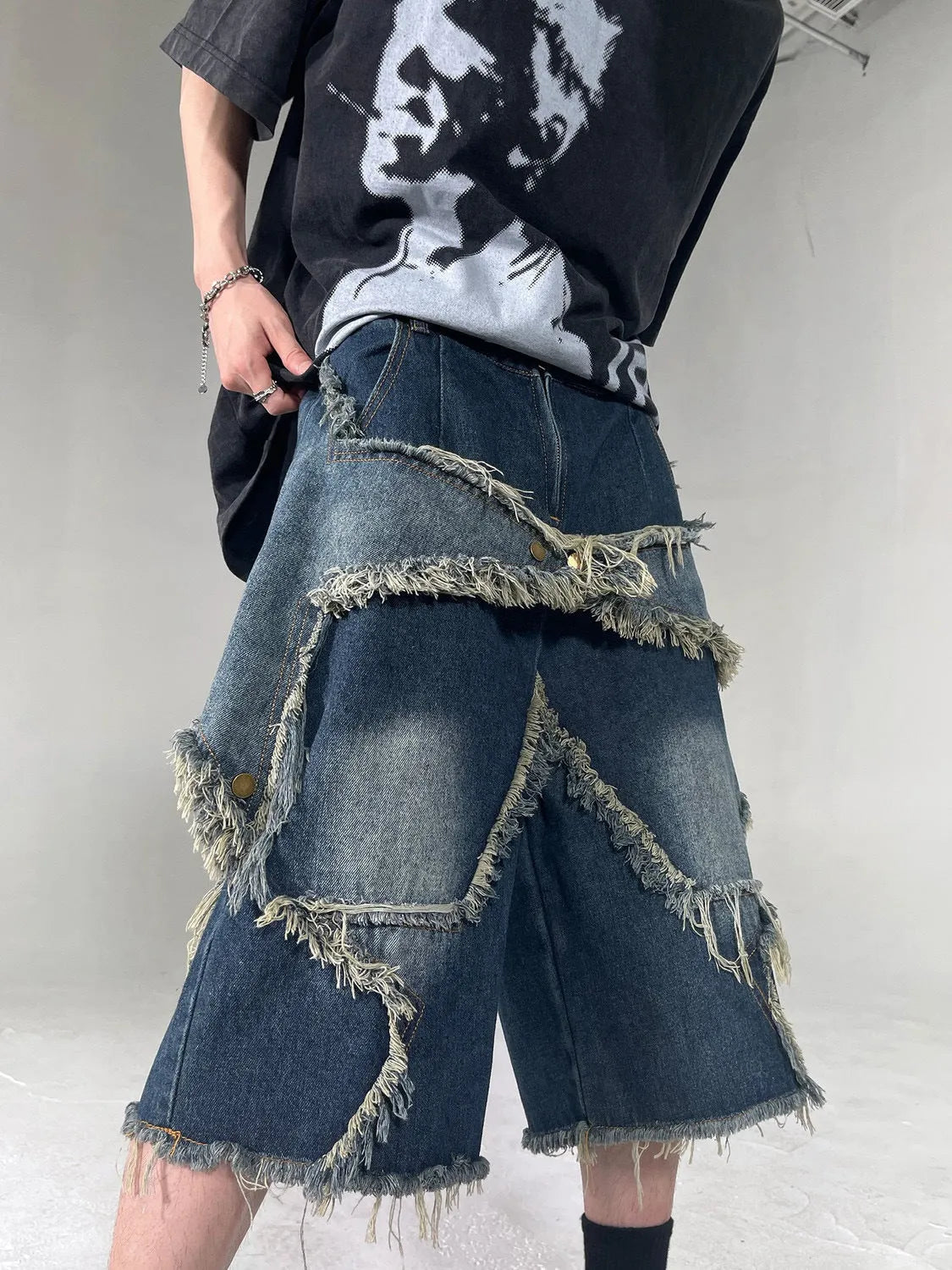 Blue denim shorts with a frayed hem and a large five-pointed star design on the leg, shown on a model.