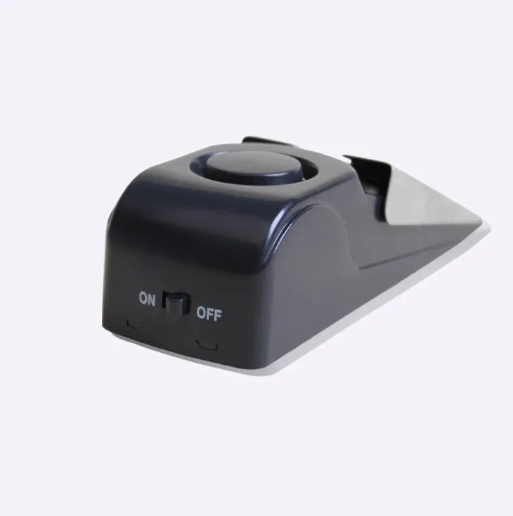 Black portable door stop alarm with wedge shape and stainless steel sensor cover.