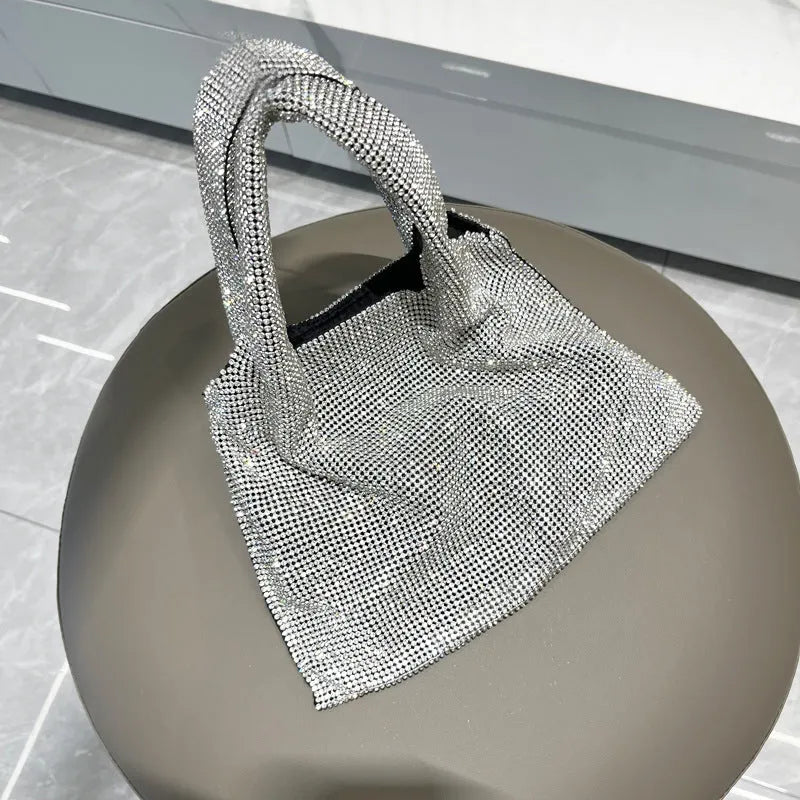 Silver handbag decorated with shiny rhinestones, made from cotton thread with one open pocket.
