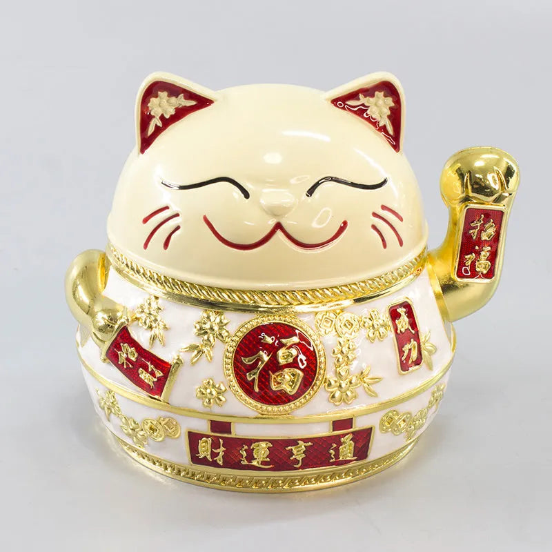 Zinc alloy Lucky Cat ashtray with cover in a gold-black finish on a table