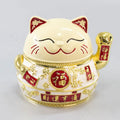 Zinc alloy Lucky Cat ashtray with cover in a gold-black finish on a table