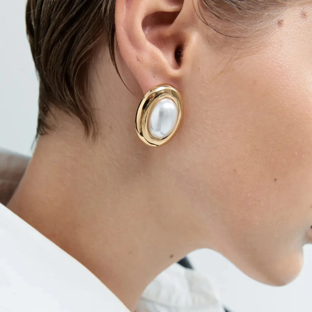 A pair of stainless steel stud earrings with a small vintage-style pearl drop and a non-fade electroplated finish.