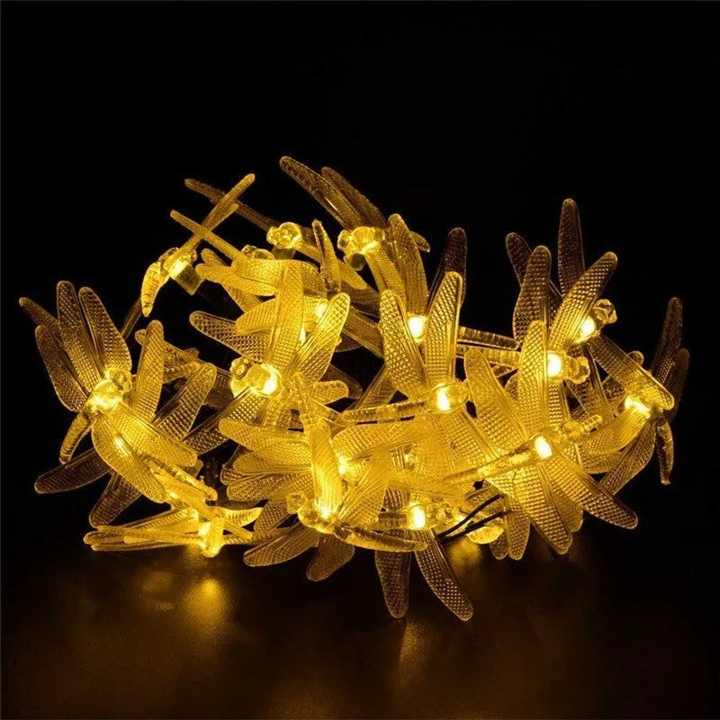 Outdoor solar-powered dragonfly string lights with garden spike, shown in a warm white glow
