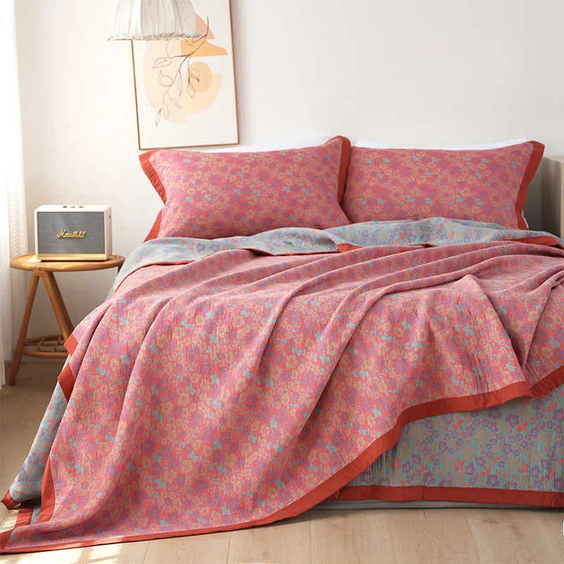 Cotton gauze floral blanket and two matching pillowcases laid out on a bed.