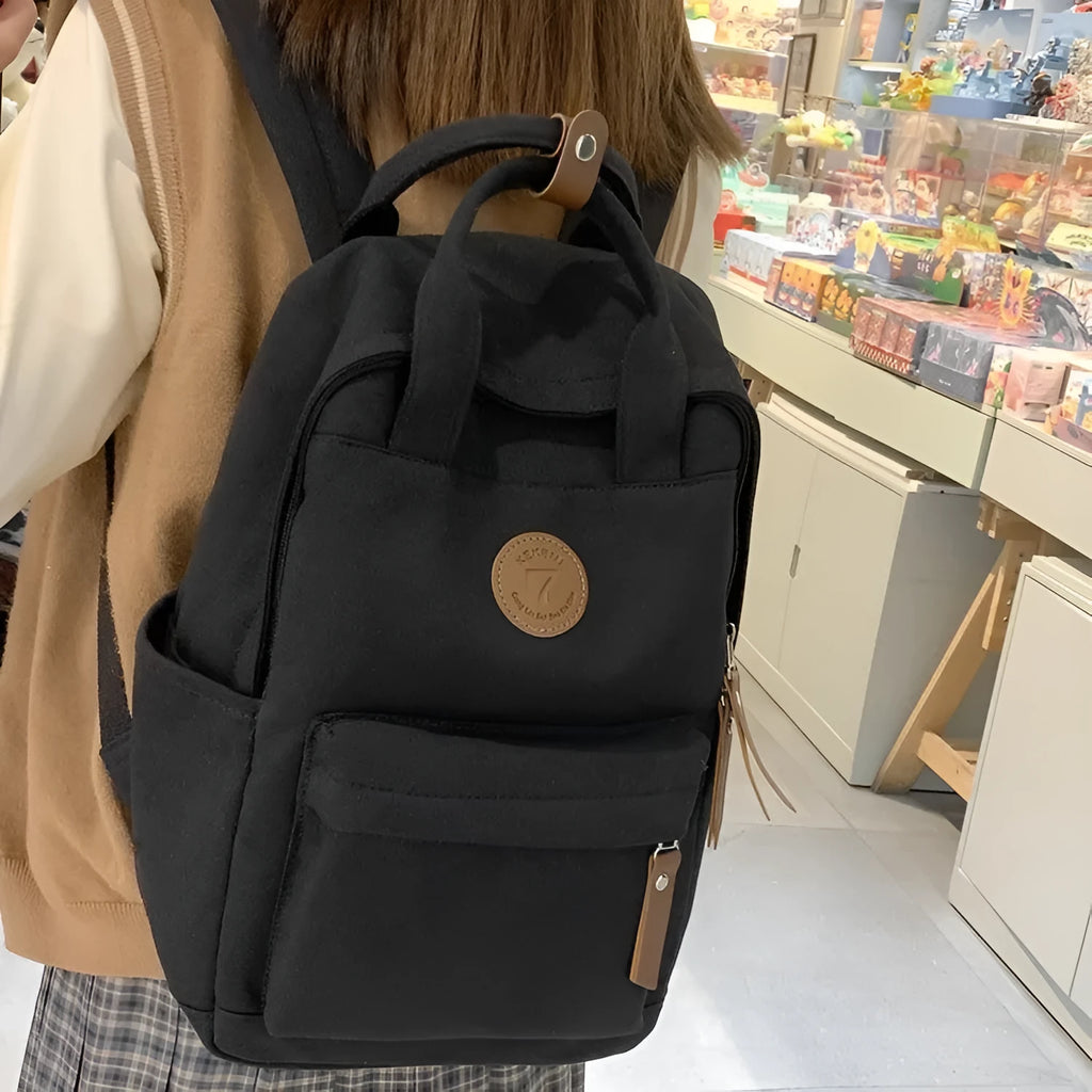 Black retro-style Oxford cloth backpack with curved shoulder straps and sewing thread detail.