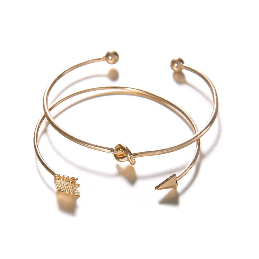 Gold women's vintage bracelet with knotted cuff design and central arrow motif
