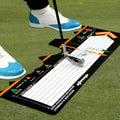 Black neoprene golf swing training pad with alignment markings on a green artificial turf surface.