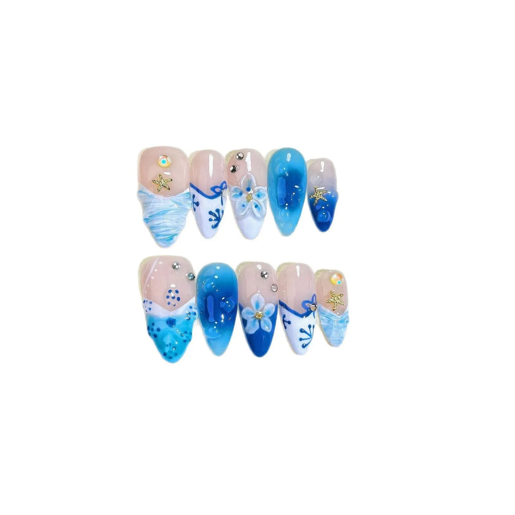 Set of blue false nails with hand-painted colour and carved summer ice design, laid out on a surface.