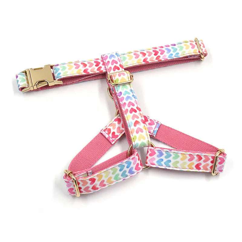 Pink dog harness with a gold buckle and a colourful heart-shaped stone on the chest strap.