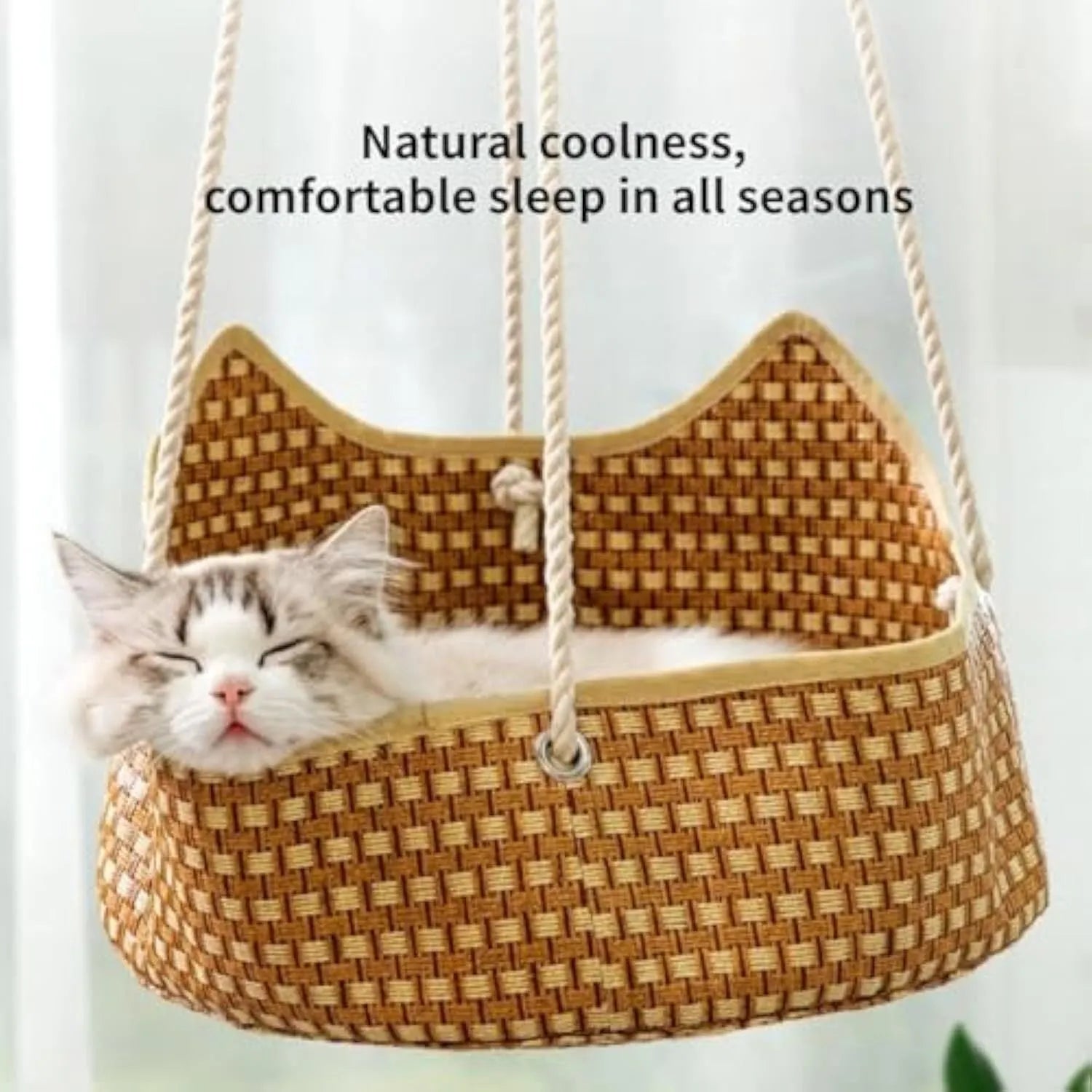 Green woven rattan cat hammock with metal hooks, hanging on a white shelf with a cat resting.
