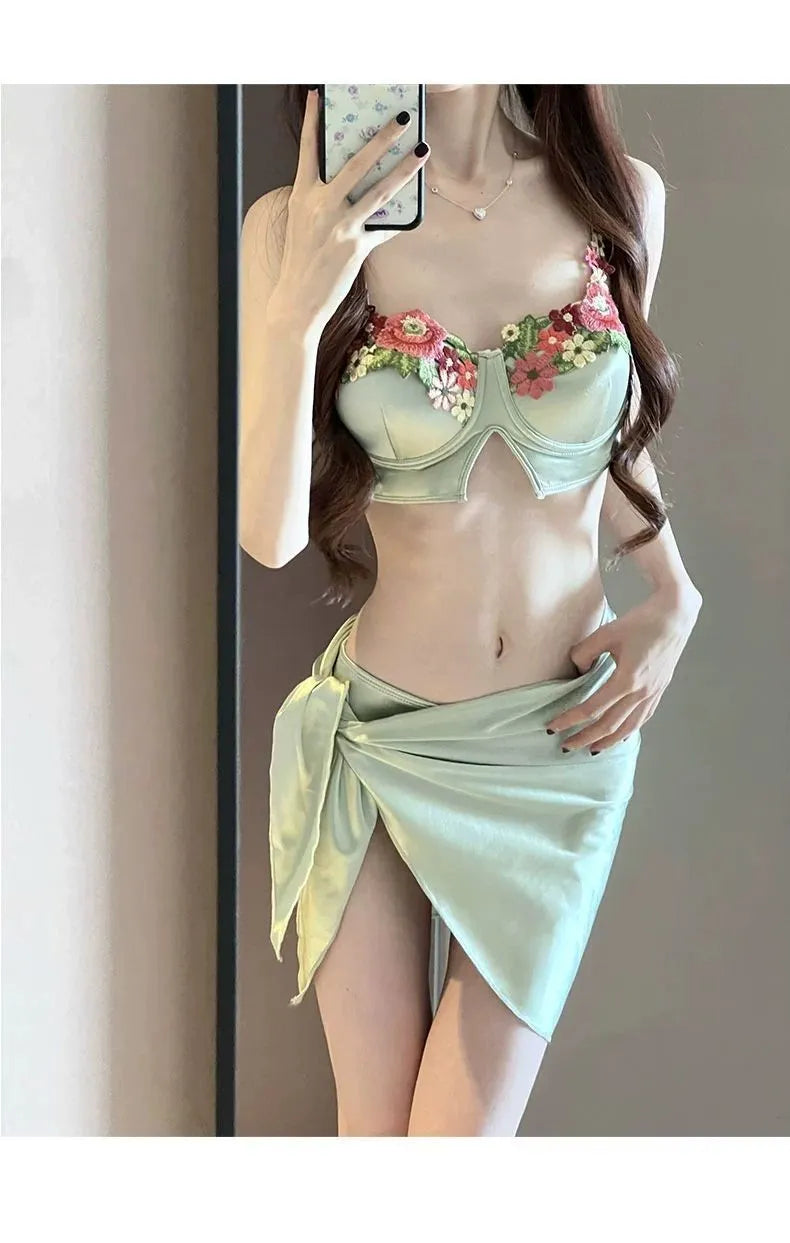 Green women's three-piece bikini swimsuit set with triangle top, briefs, and a short skirt on a mannequin.
