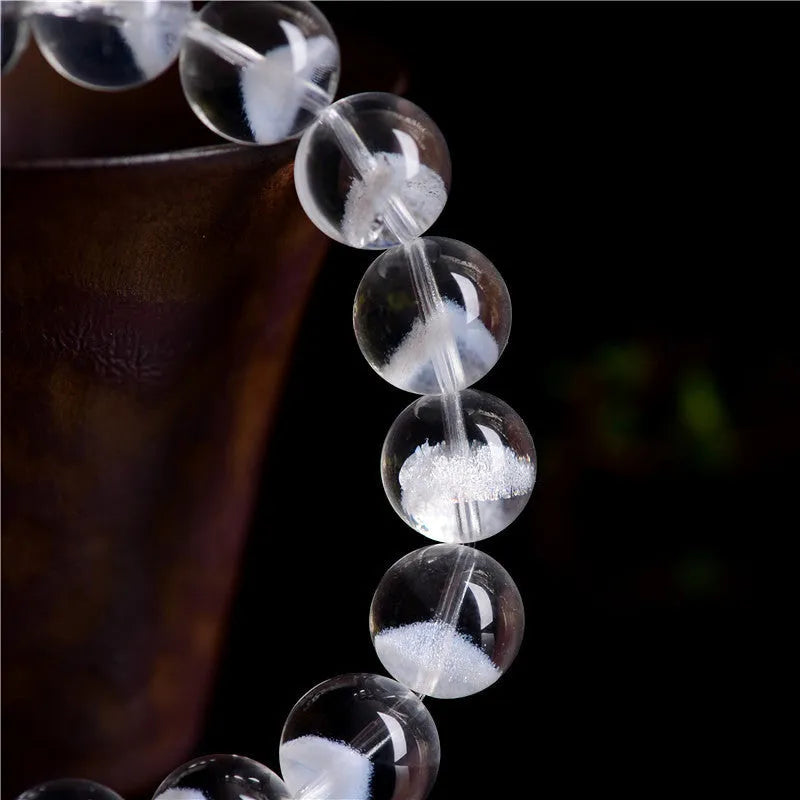 Women's white crystal pyramid bead bracelet with Ruyi design motif on a wrist.