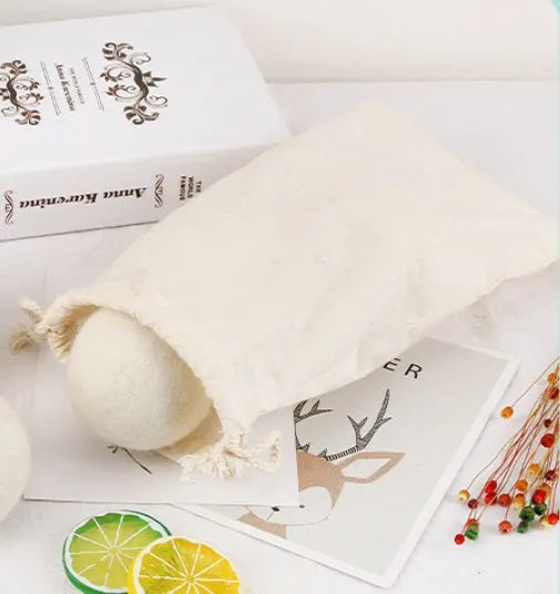 Handmade natural wool felt drying ball for laundry next to a plain cotton storage bag.