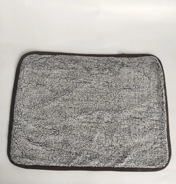 Waterproof urine proof pet blanket in grey with black and white bottom on a kennel bed