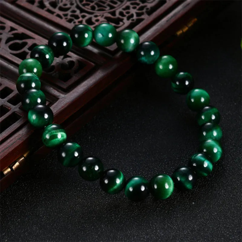 Natural green tiger eye stone bracelet with polished spherical beads in geometric design on wrist.