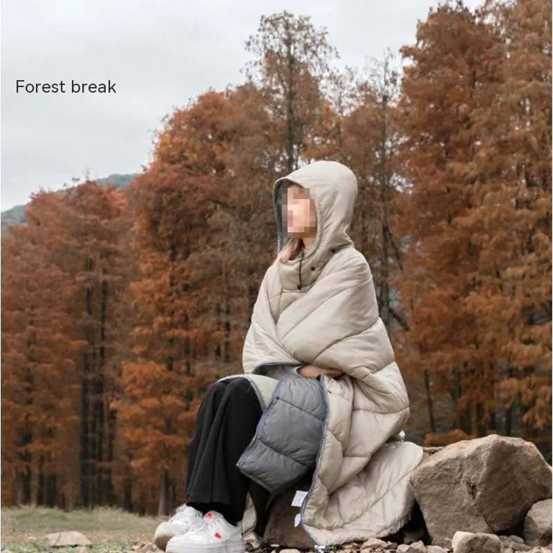 Grey outdoor cloak sleeping bag worn as a cape, showing its large 200x140cm size and hooded design.