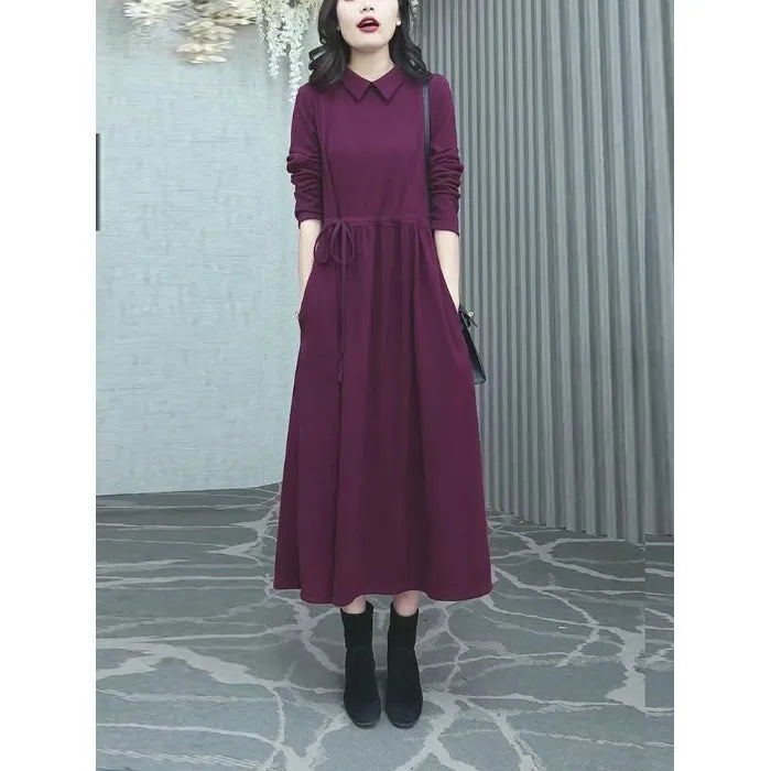 A purplish red plus size long sleeve dress with an ankle-length skirt on a mannequin.