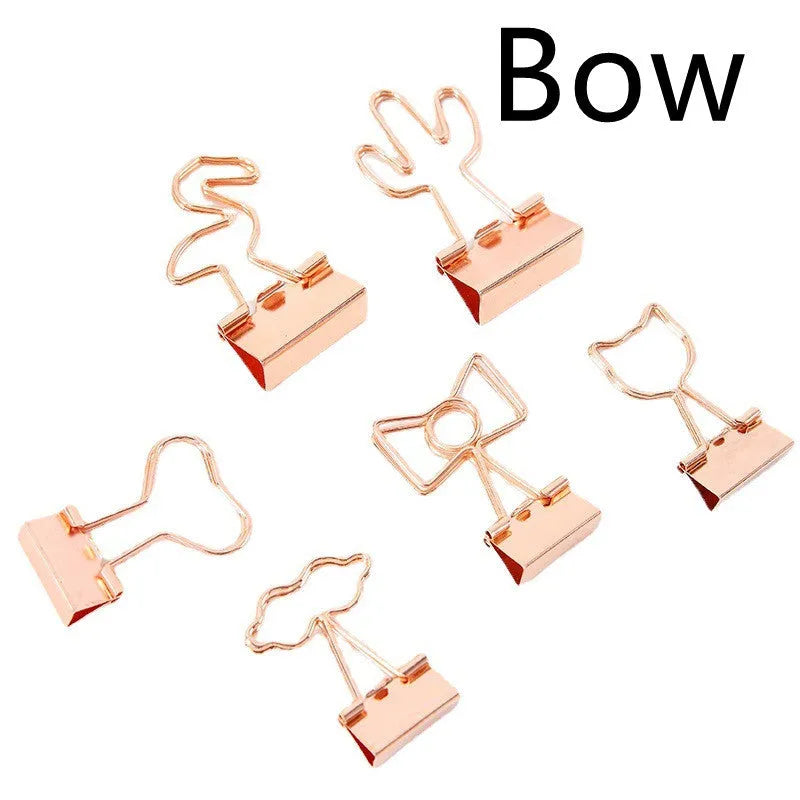 Small gold metal office clip with a decorative bow charm on a long tail.