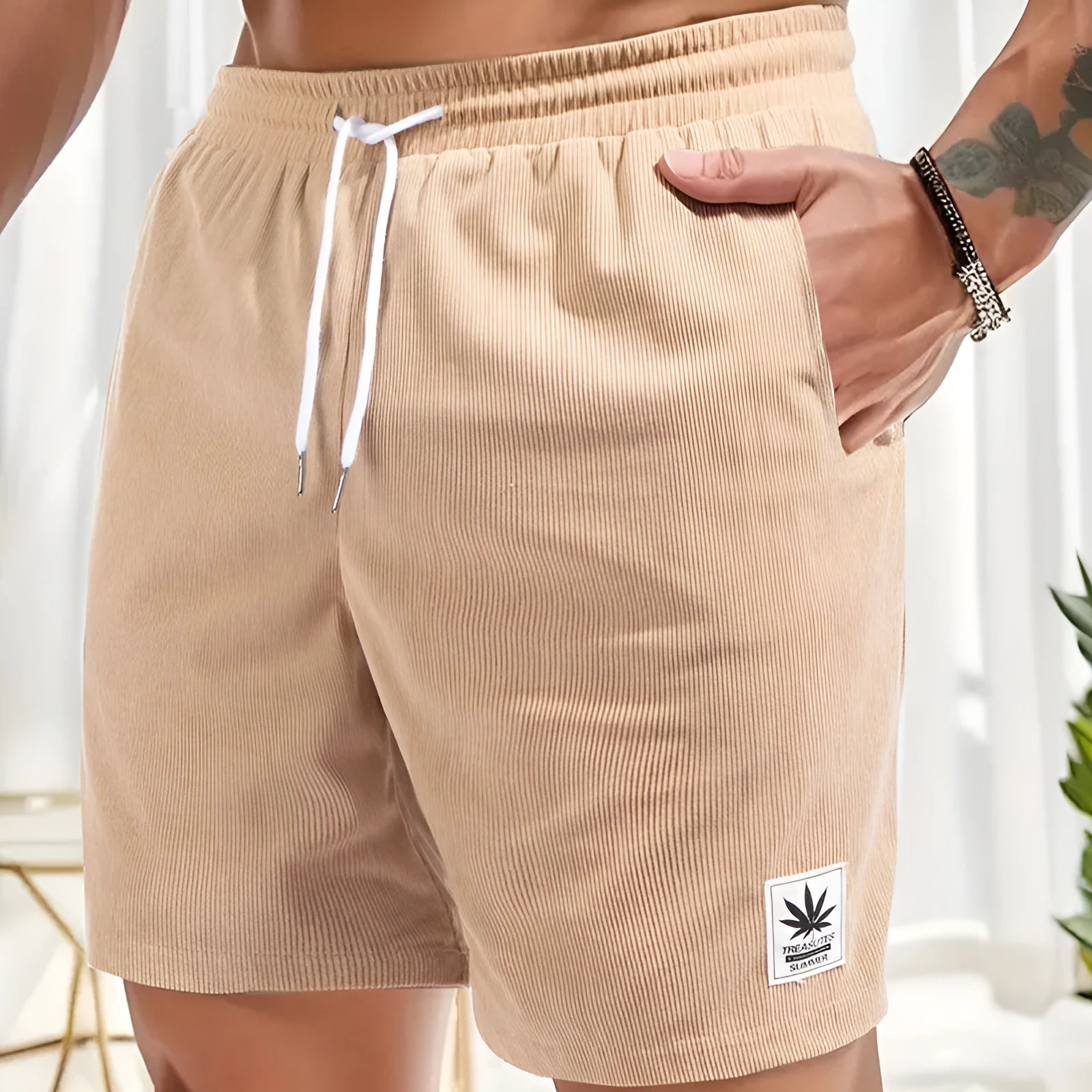 Man wearing grey straight-cut elastic drawstring summer shorts on a beach.