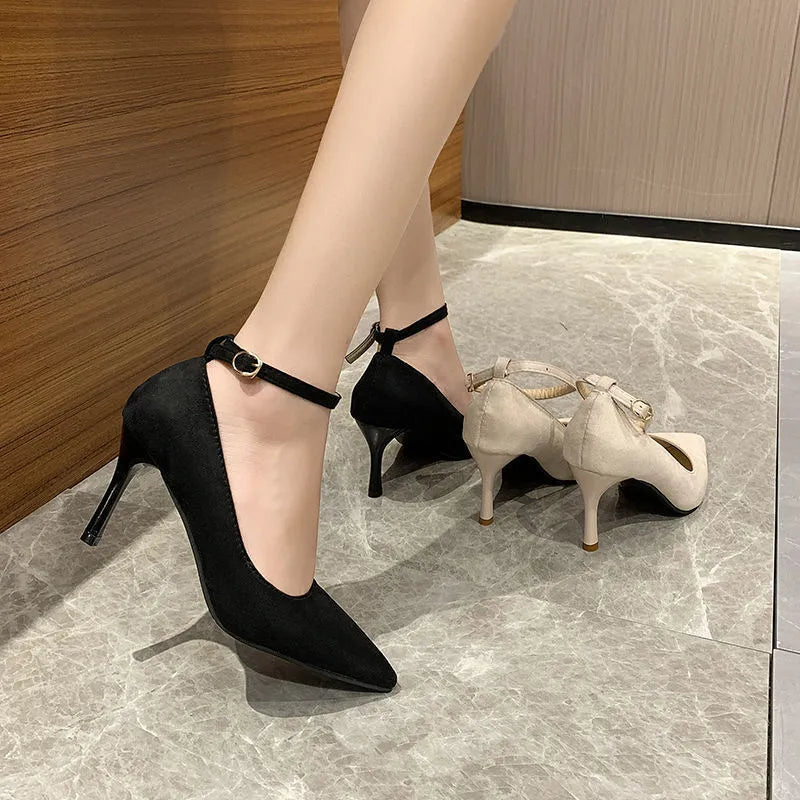 Women's black stiletto heel pump shoes with a buckle strap on the side.