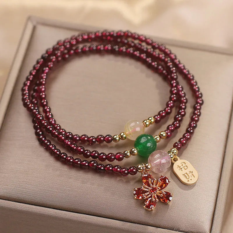 Women's natural crystal bracelet in pomegranate red cherry blossom colour with sequin details on strap.