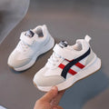 A pair of children's casual sneakers with a Velcro strap, shown in a neutral solid colour.
