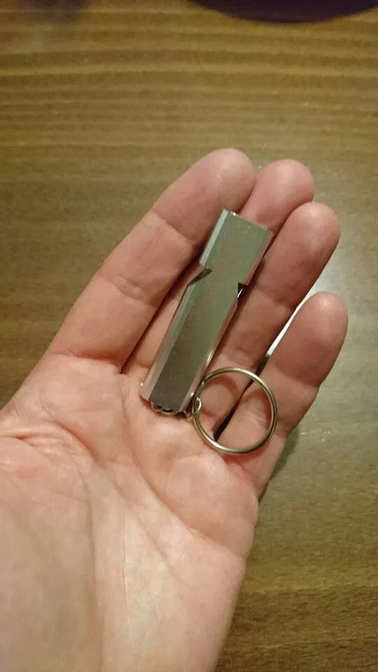 Silver and gold aluminium alloy outdoor survival whistle with double hole design.