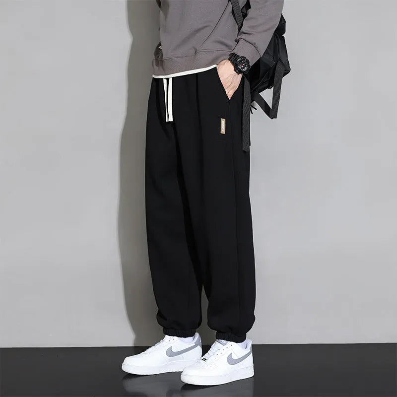 Men's loose grey casual sports trousers with drawstring waist on a plain background