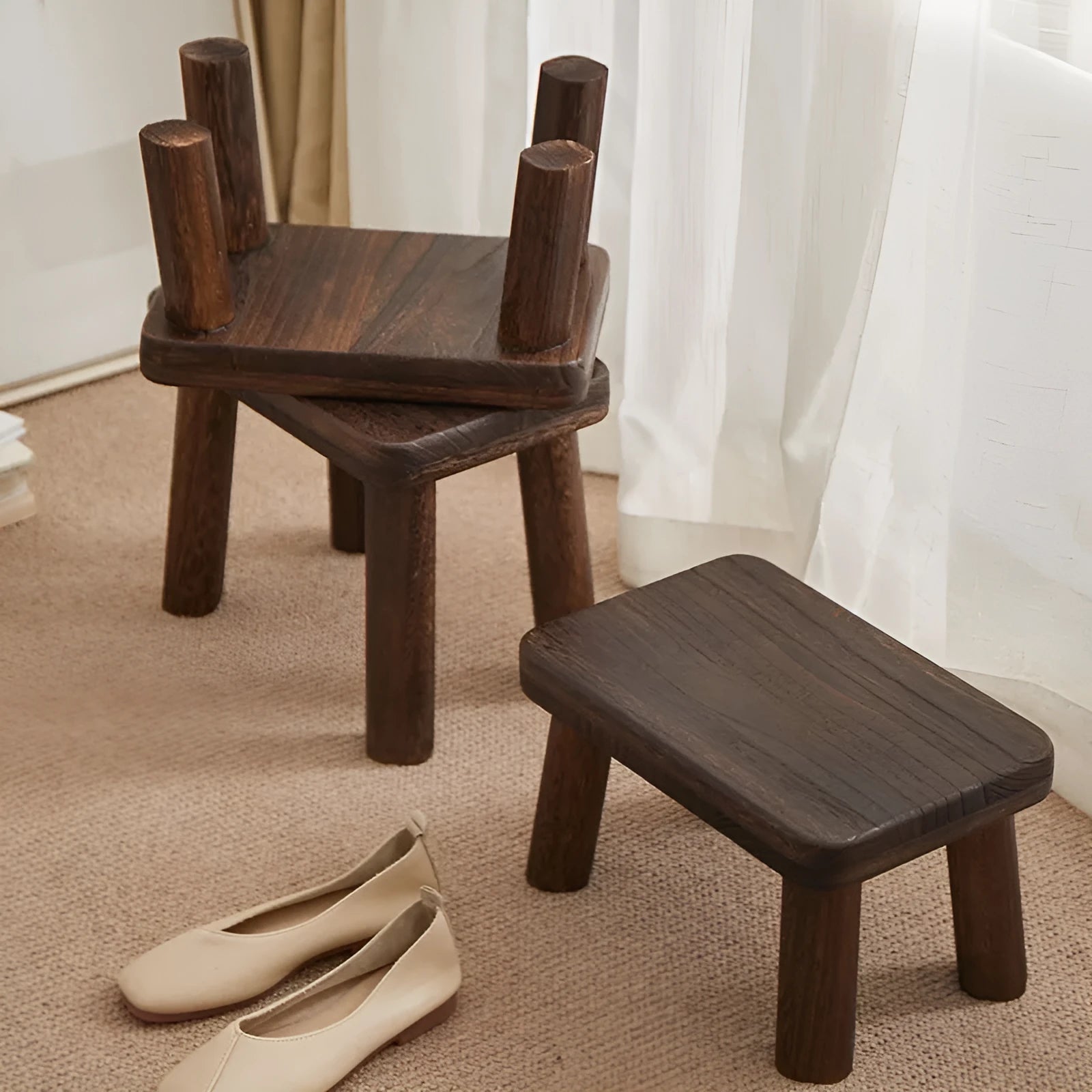 A rustic distressed wooden stool with bracket legs, used as a shoe changing bench in a hallway.