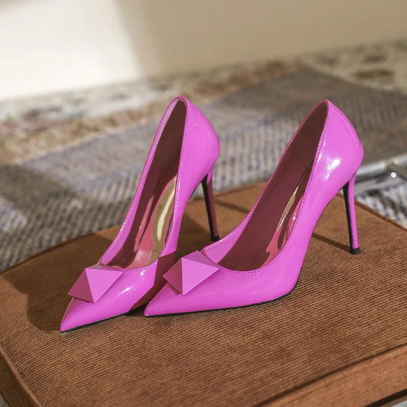 Pink women's patent leather pointed toe stiletto high heels with a buckle on the strap.
