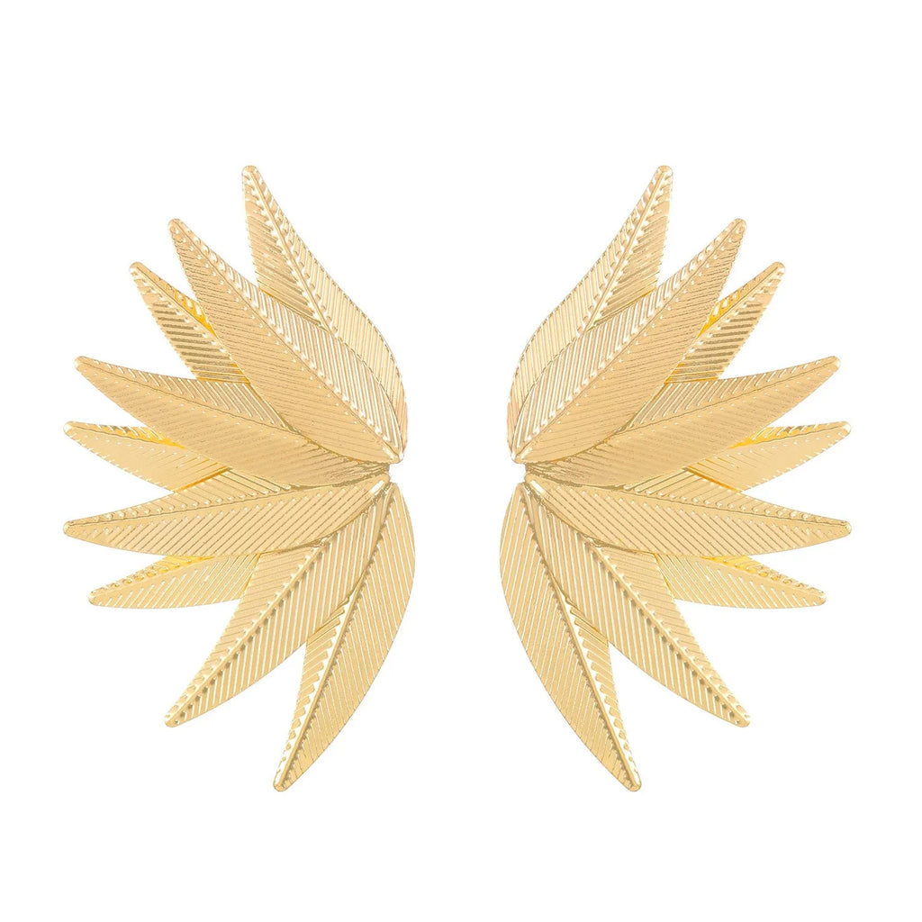 A pair of gold alloy drop earrings shaped like leaves, lying on a surface.