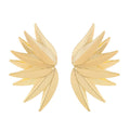 A pair of gold alloy drop earrings shaped like leaves, lying on a surface.