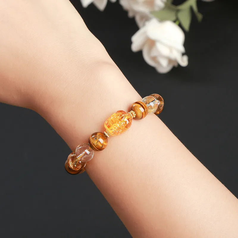 Close-up of a unisex bracelet with 10mm yellow tiger's eye and citrine round beads and a detailed beeswax pi xiu charm.