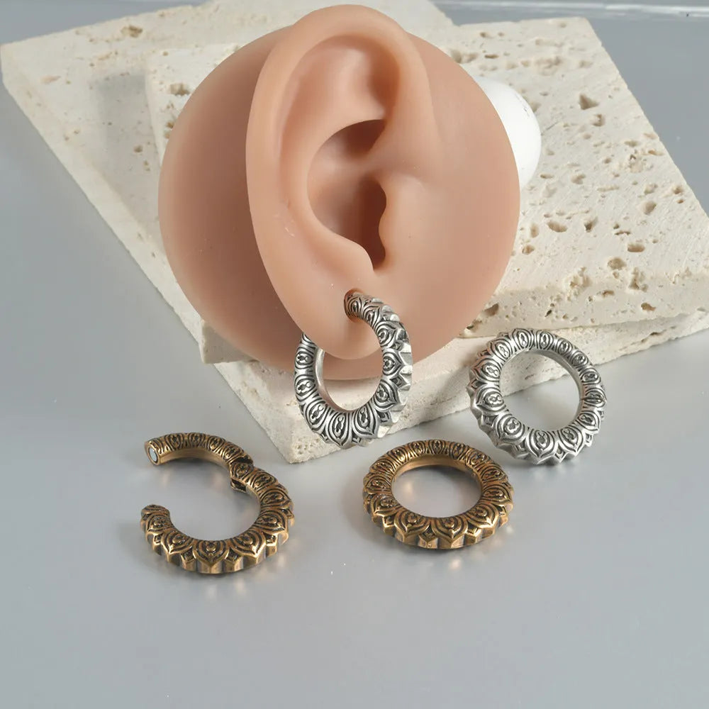 A pair of large antique silver hoop earrings with a hollow-out geometric dragon shape design.