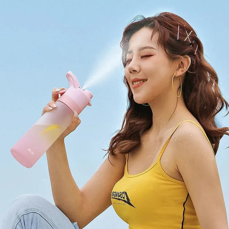 Large pink plastic spray water bottle with a handle strap and leakproof lid on a gym bag.
