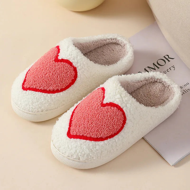 Women's plush slippers with cartoon love design, showing round toe and non-slip PVC sole.