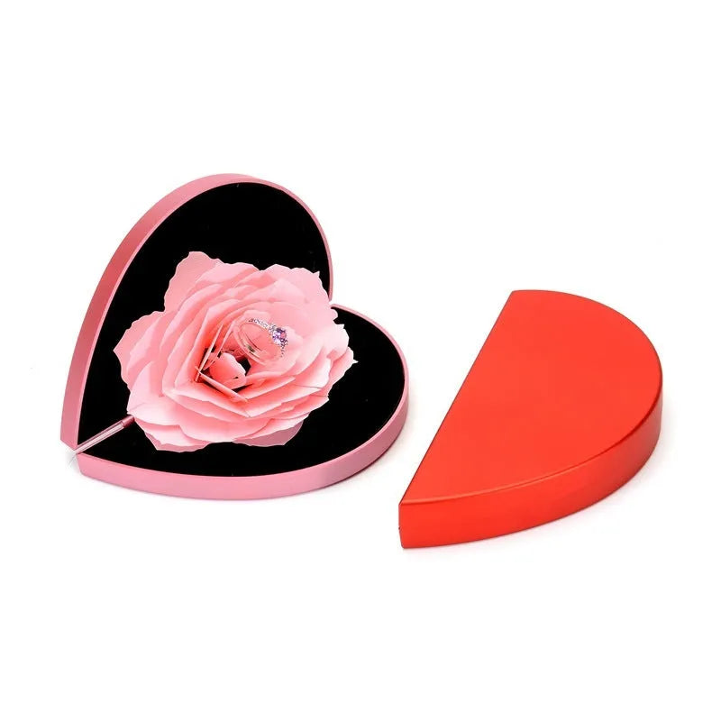 Red 3D heart-shaped plastic ring box with a rotating white rose decoration on top.